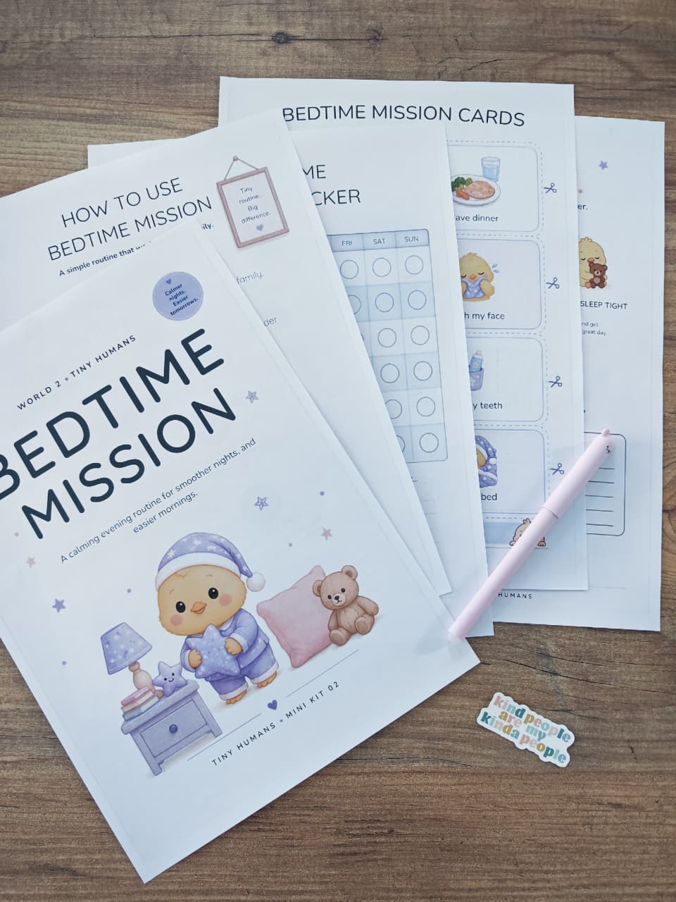 Printed Bedtime Mission routine pages and tracker arranged on a wooden table, with a pink pen beside them.